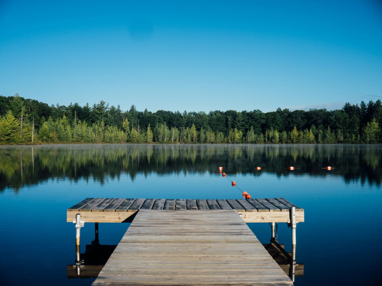 Holzsteg auf einem stillen See am Morgen